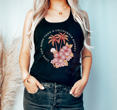 A woman wearing a black tank top with a floral design and text, standing against a light blue background.